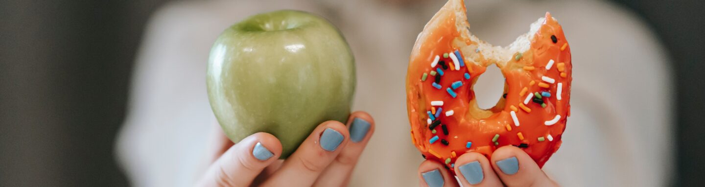 Frau hält Donut und Apfel