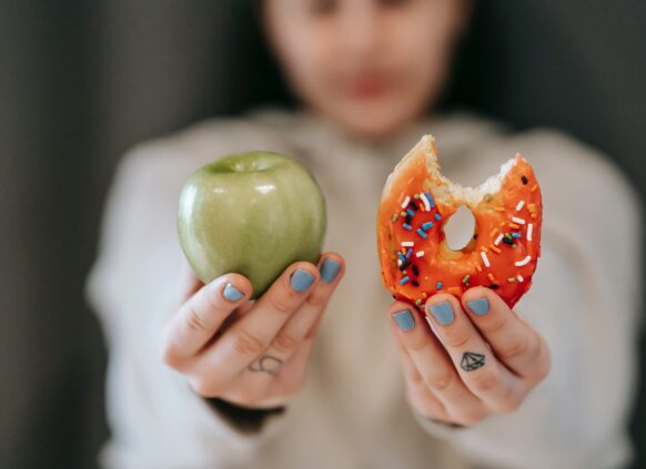 Frau hält Donut und Apfel