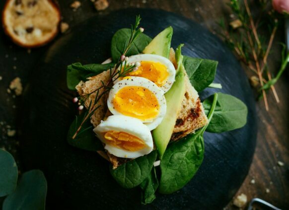 Ein Brot mit Salat, Avocado und Ei ist auf einem Teller angerichtet.