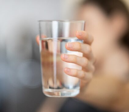 Person hält ein Glas Wasser in der Hand.