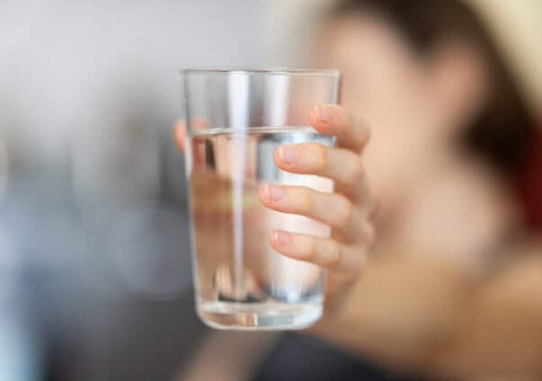 Person hält ein Glas Wasser in der Hand.