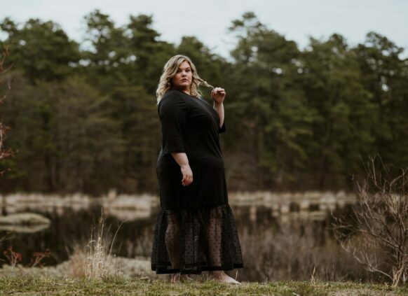 Plus size Frau steht im Kleid an einem See