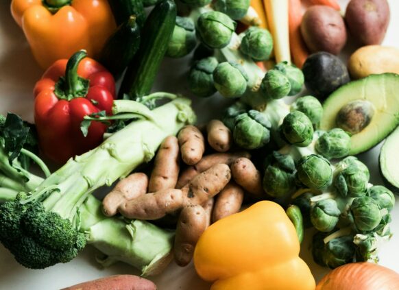 Brokoli, Süßkartoffel, Paprika, Zwiebel, Rosenkohl und Kartoffeln liegen auf einer Platte