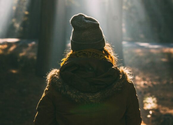 Eine Frau mit Mütze im Wald von hinten zu sehen