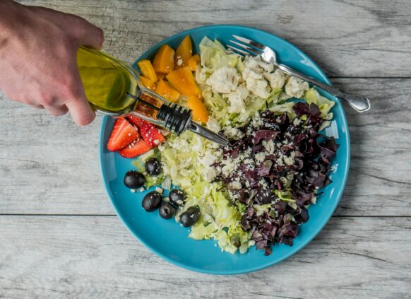 Salat wird mit Öl betreufelt.