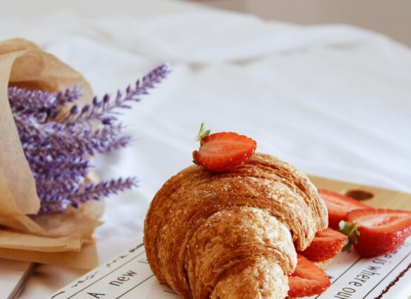 Croissant mit Erdbeeren getoppt auf einem Schneidebrett.