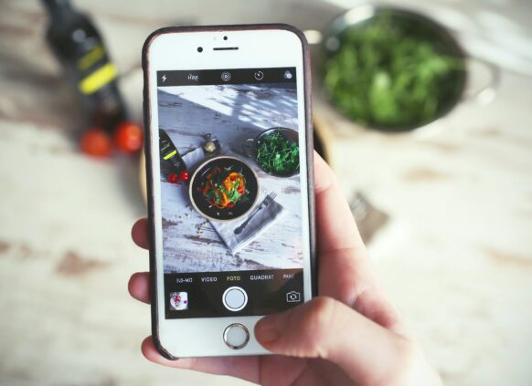 Das Display eines Smartphones zeigt durch die Kamera einen gesunden Salat.