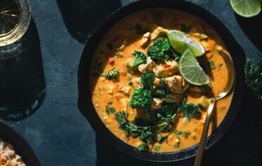 Ein Kokos Curry in einer Bowl auf einer Platte.