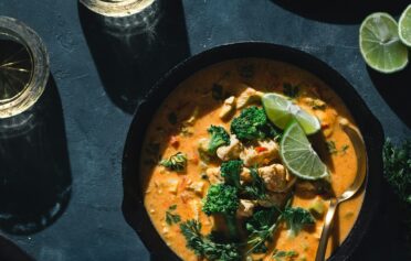 Ein Kokos Curry in einer Bowl auf einer Platte.