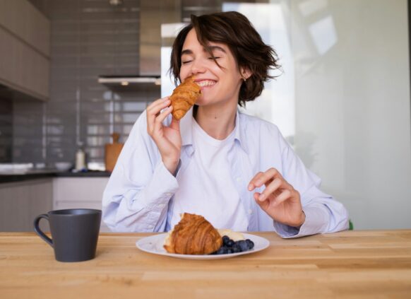 Junge Frau ist freudig ein Croissant.