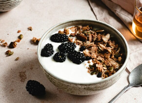 Eine Schüssel mit Joghurt, Brombeeren und Granola.