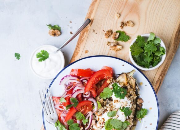 Aubergine mit Tomatensalat auf einem weißen Teller garniert.