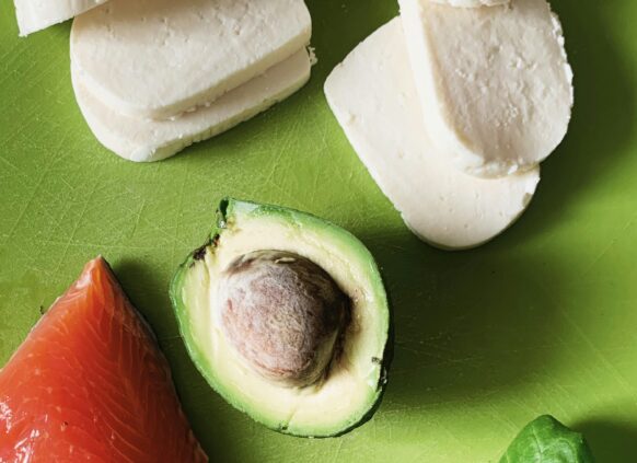 Avocado, Lachs und Mozarella liegen auf einer grünen Oberfläche