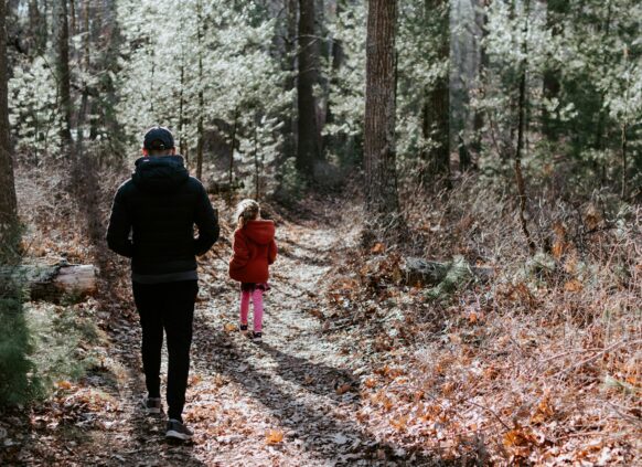 Ein Vater macht mit seiner Tochter im Wald einen Verdauungsspaziergang.