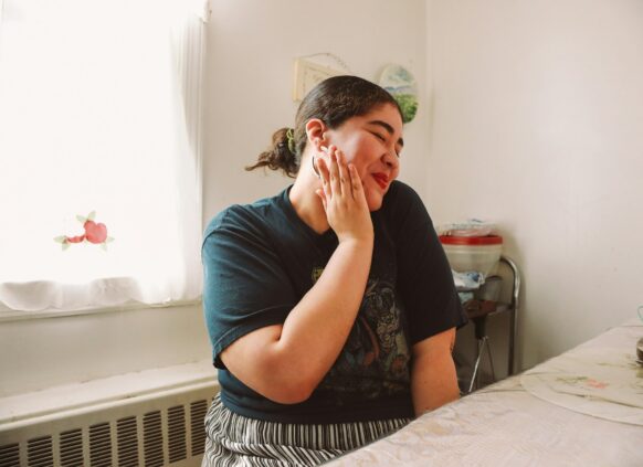 Eine junge lächelnde plus size Frau sitzt an einem Tisch.