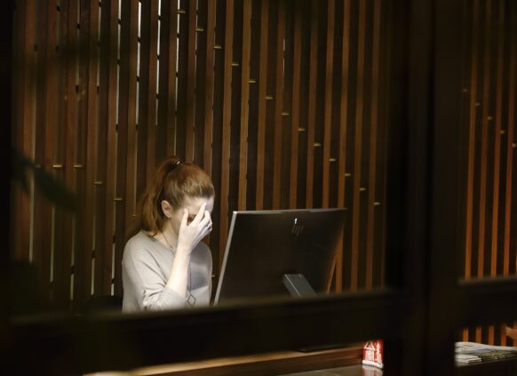 Eine getresste Frau sitzt vor einem Computer