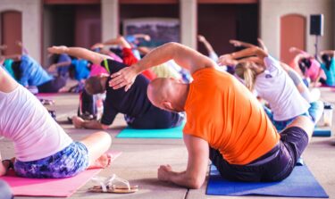 Eine Gruppe von Männern und Frauen macht gemeinsam Yoga und isometrische Übungen.