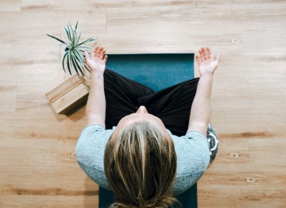 Eine Frau meditiert auf einer Yoga Matte.