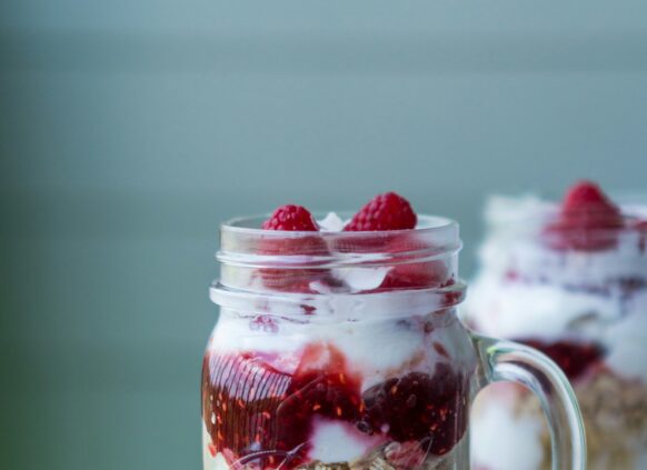 Ein Glas mit Schichtjoghurt mit Haferflocken und Erdbeeren.