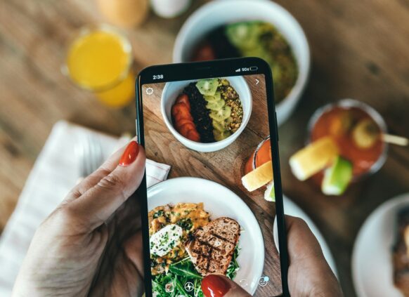 Ein Auschnitt, auf dem zu sehen ist, wie jemand ein Bild von seinem gesunden Essen mit einem Smartphone macht.