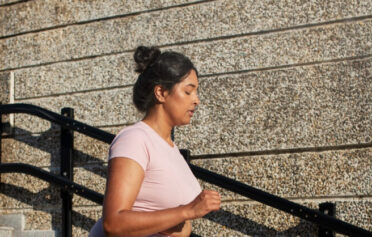 Eine Frau joggt einige Treppen in der Stadt hinunter.