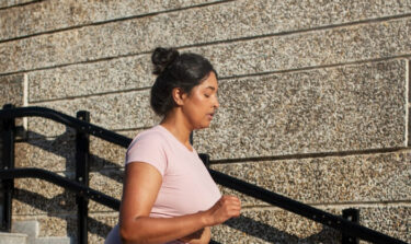 Eine Frau joggt einige Treppen in der Stadt hinunter.