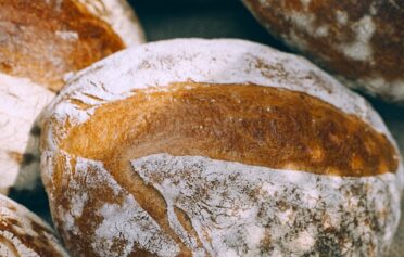 Drei Leibe frisches Brot sind auf einem Leinentuch platziert.