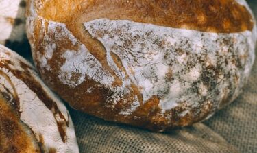 Drei Leibe frisches Brot sind auf einem Leinentuch platziert.