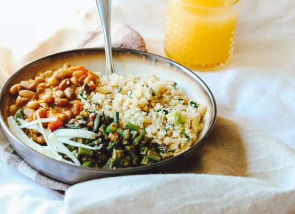 Ein Teller mit einer Gemüse-Quinoa-Salatbowl und einem Glas Orangensaft dazu.