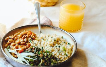 Ein Teller mit einer Gemüse-Quinoa-Salatbowl und einem Glas Orangensaft dazu.