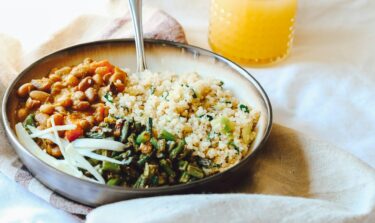 Ein Teller mit einer Gemüse-Quinoa-Salatbowl und einem Glas Orangensaft dazu.