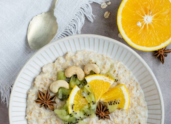 Eine Schale mit Porridge, garniert mit Obst und Cashews.