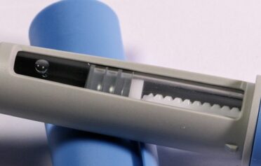 Eine Nahaufnahme einer Anehmspritze, die offen auf der Kappe der Nadel liegt.