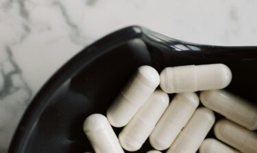 Magnesium-Pillen in einer schwarzen Schale auf einem Marmor Hintergrund
