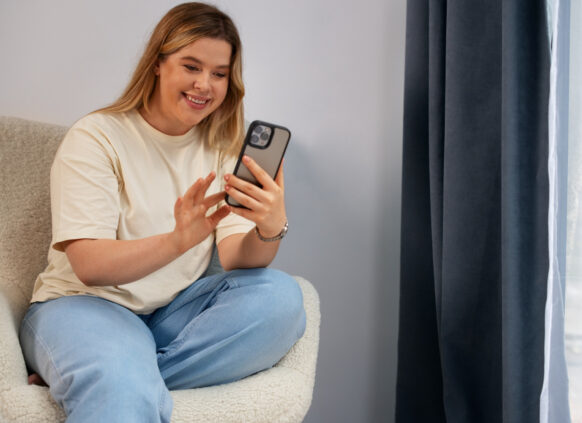 Frau lächelt während sie auf ihr Handy schaut