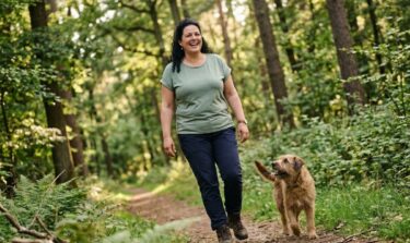 KI-generiert: Eine Frau spaziert mit ihrem Hund durch den Wald