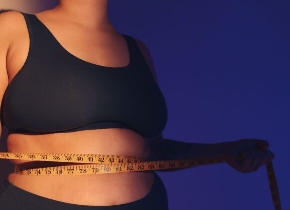 Frau schlingt Maßband um ihre Taille