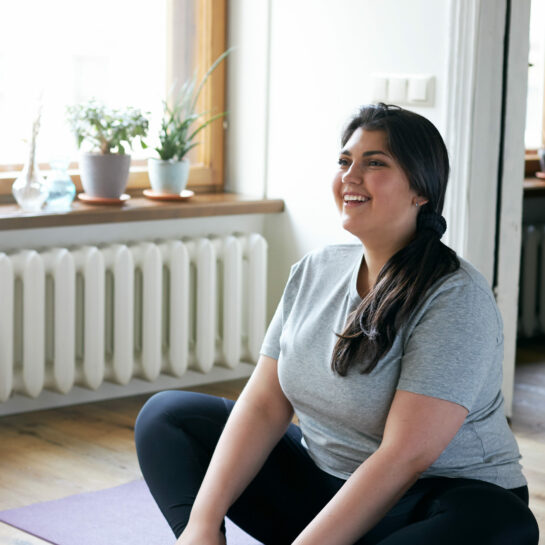 Glückliche junge Frau auf einer Yogamatte