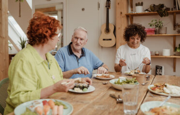 Zwei Frauen und älterer Mann essen zusammen