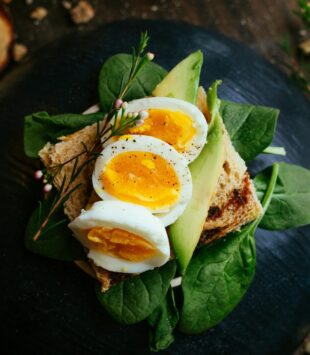 Ein Brot mit Salat, Avocado und Ei ist auf einem Teller angerichtet.