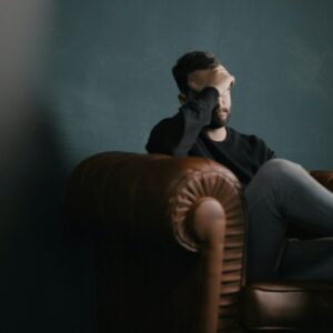 Ein Mann sitzt nachdenklich auf einem Sofa.