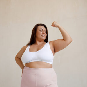 Plus size model winkelt ihren linken Arm an und wirkt stark.