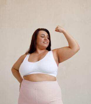 Plus size model winkelt ihren linken Arm an und wirkt stark.