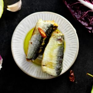 Auf einem weißen Teller wird Fisch serviert.