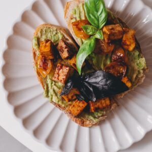Brot mit Guacamole und Tofu auf weißem Teller
