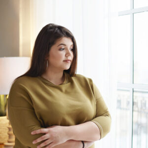 Junge Frau mit Übergewicht am Fenster