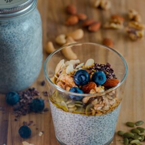 Ein Glas mit Chiapudding, getopped mit frischen Beeren und Granola.
