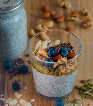 Ein Glas mit Chiapudding, getopped mit frischen Beeren und Granola.
