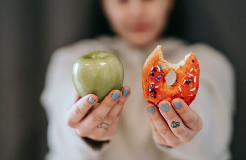 Frau hält einen Apfel und Donut