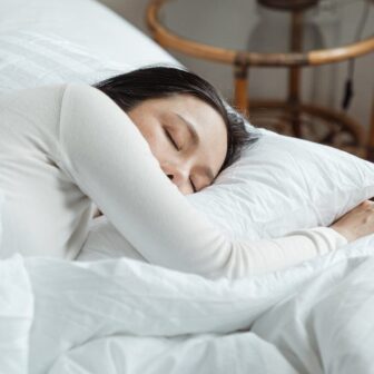 Frau schläft in einem Bett mit weißer Bettwäsche